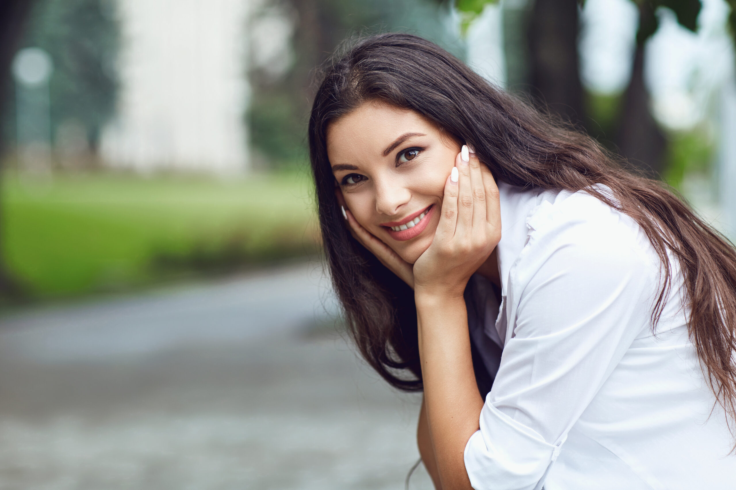 Beautiful happy brunette woman smiling outdoors on city street. Portrait of a girl.